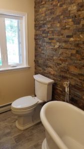 updated bathroom in Ohio with free standing tub and stone feature wall