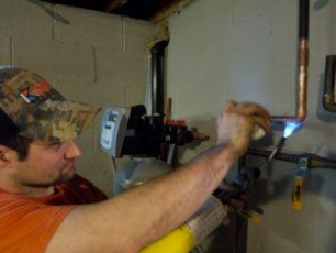 Kobella plumber working on water heater in basement