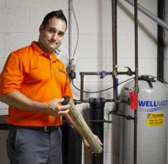 Kobella technician working on plumbing and HVAC in basement