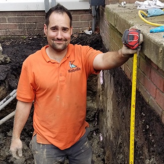 A Kobella technician digging outside a customer's home for a piping project