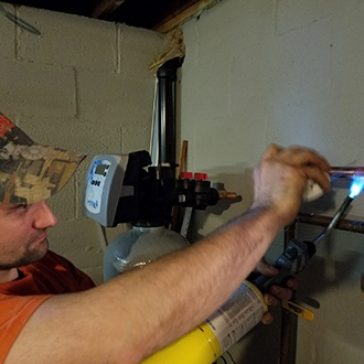 A technician repairing copper pipes with a blowtorch