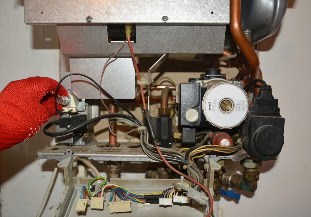 HVAC technician in red gloves repairing a gas boiler