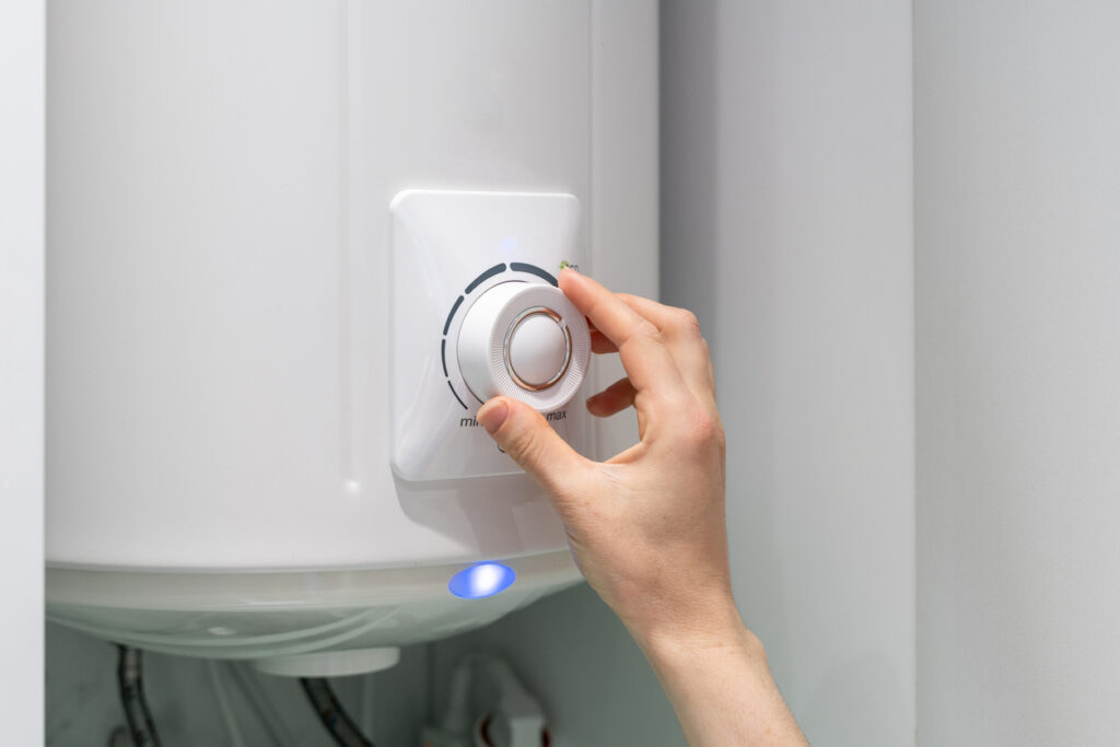 person turning up the dial on a white boiler